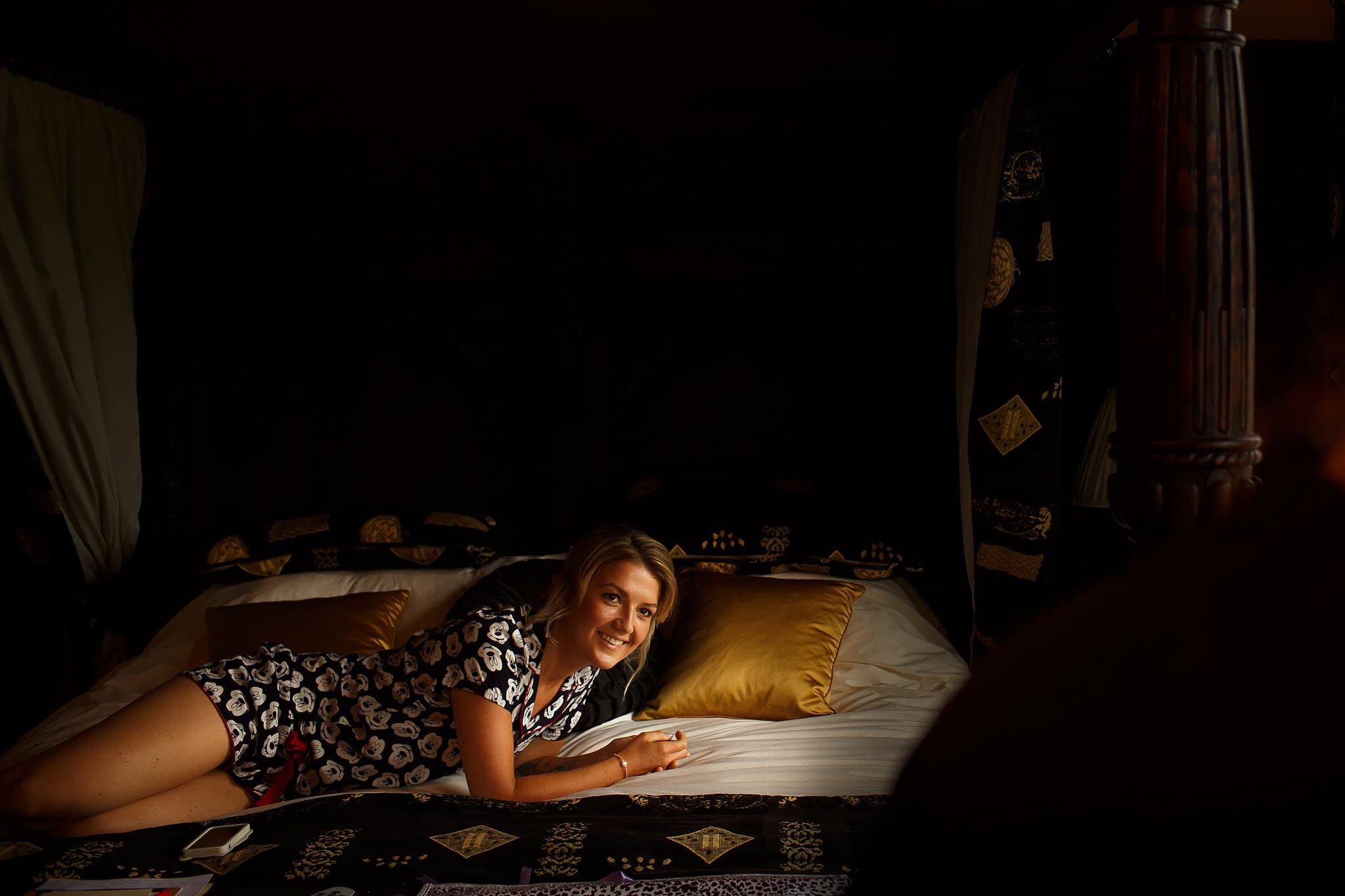 Bride smiling lying across the bed - great hall at mains wedding photography