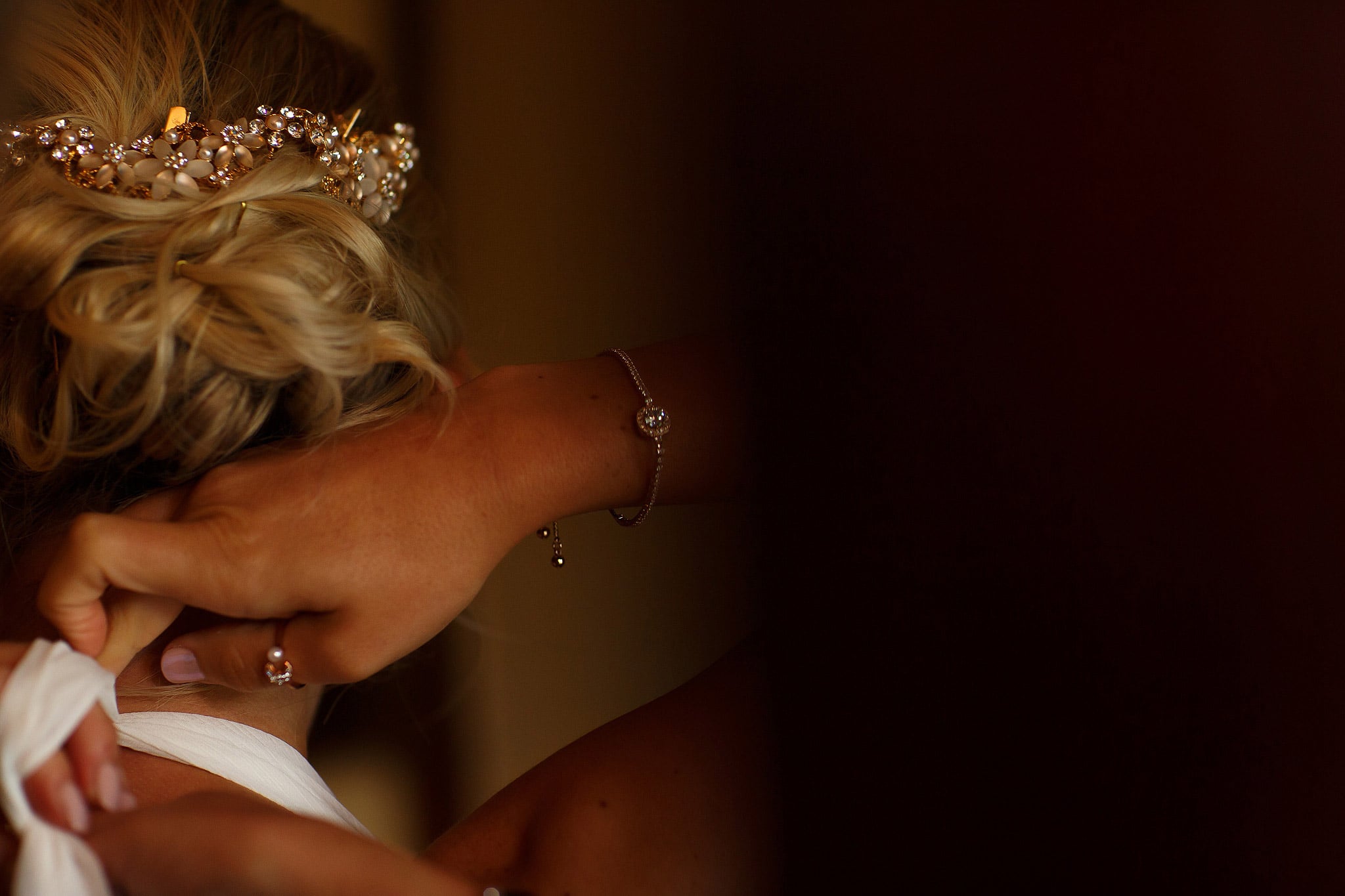 Bride having the last button fastened on her wedding dress - great hall at mains wedding photography