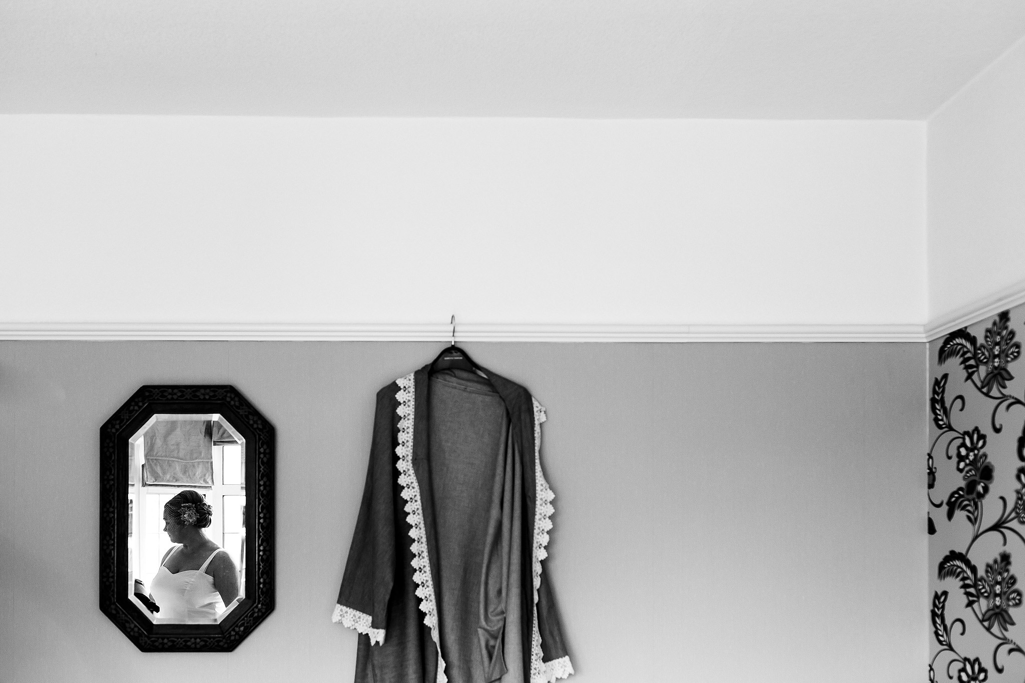 bride in reflection of mirror as she reaches for wedding dress 