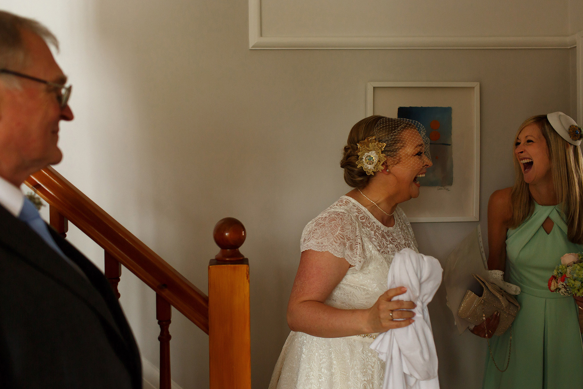 bride laughing with bridesmaids wearing birdcage veil