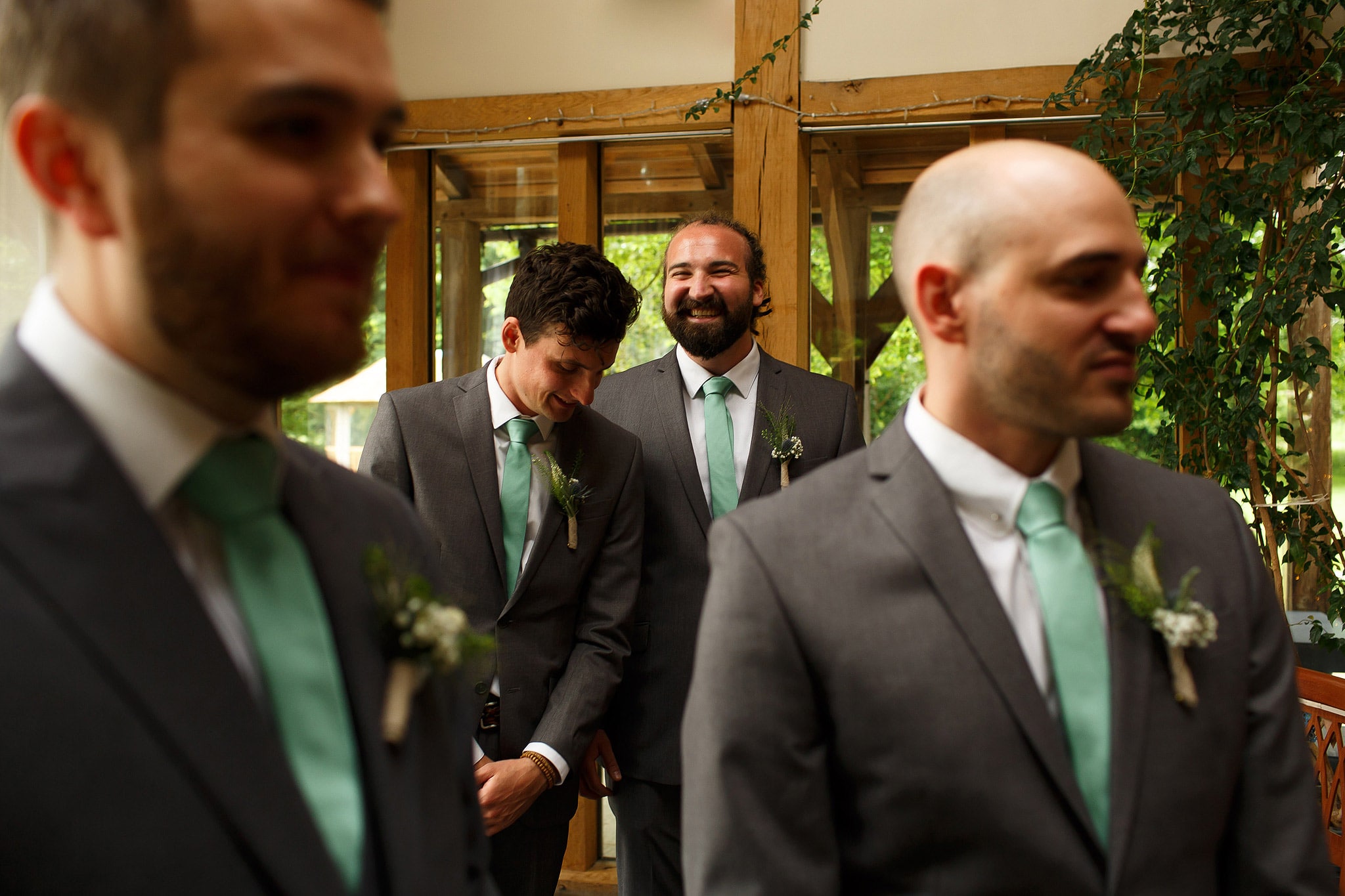Groomsmen waiting at the top of the wedding aisle wearing grey suits and mint green ties
