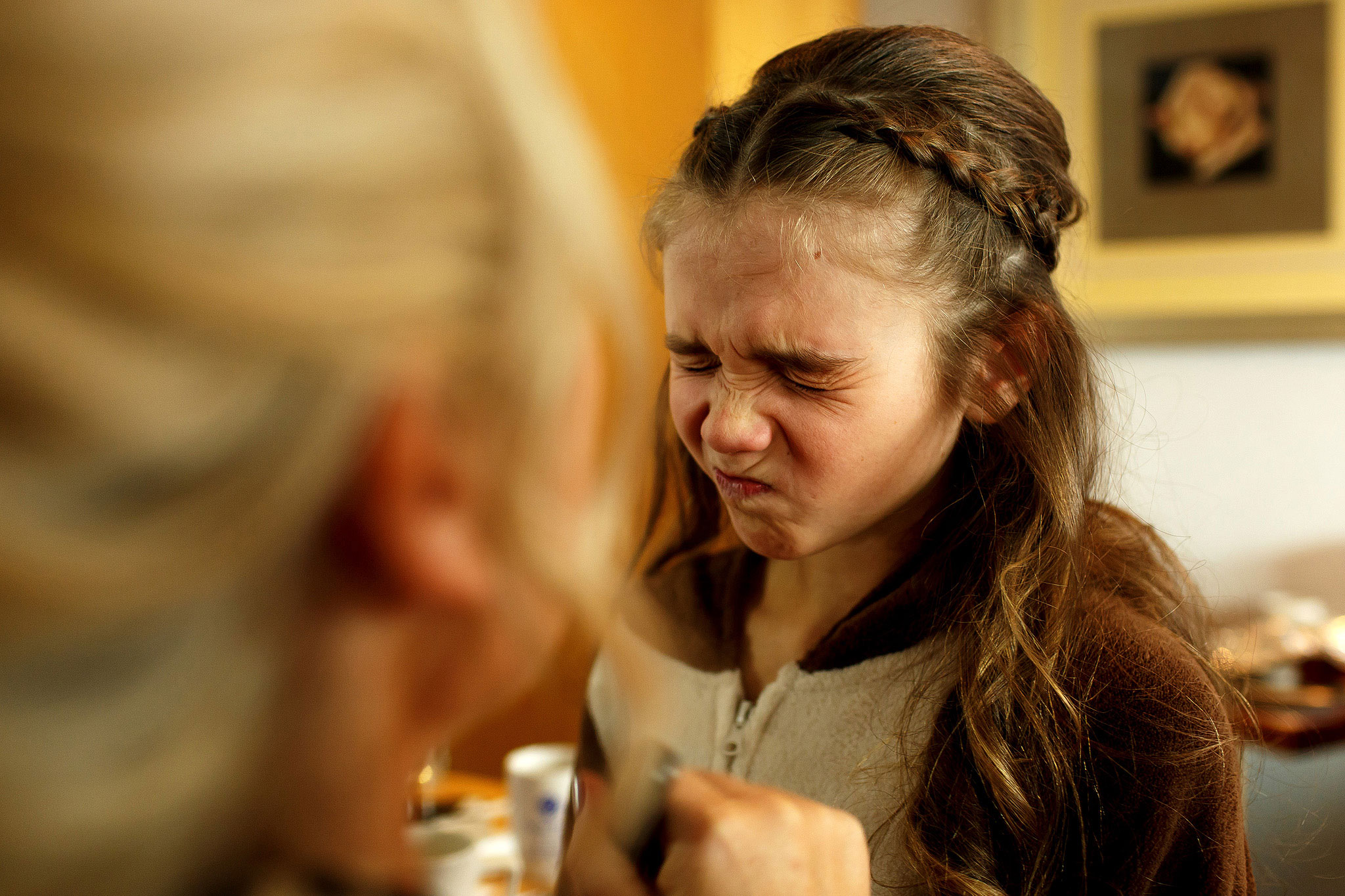 Flower girl scrunching up her face while she has make up applied on wedding day morning