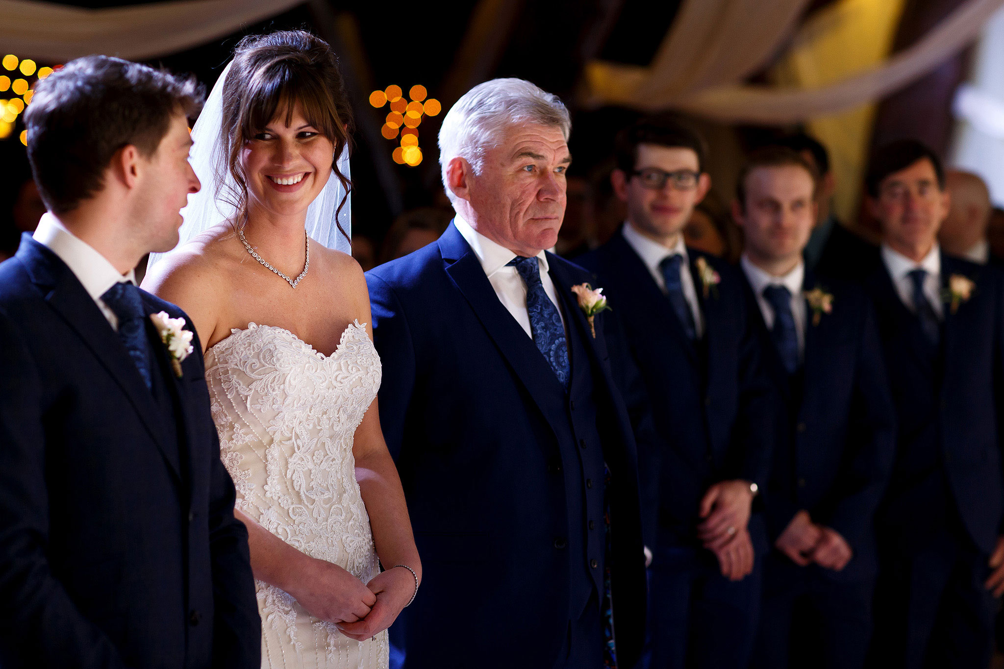 Bride wearing strapless lace wedding dress smiling towards her groom at the top of the aisle during Rivington Hall Barn civil ceremony