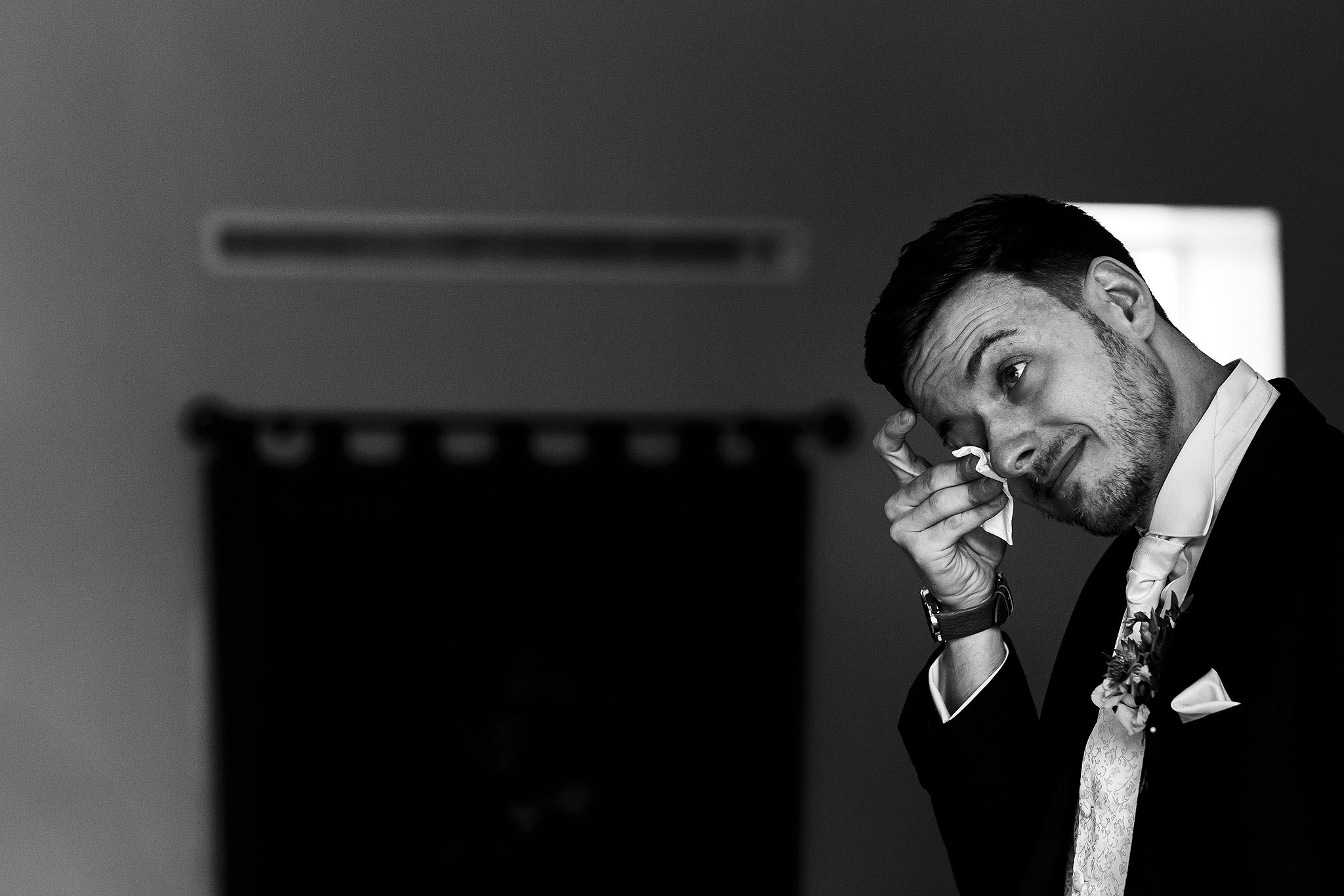 Black and white photograph of groom feeling emotional wiping eyes with tissue - The Villa at Wrea Green Wedding Photography - Toni Darcy Photography