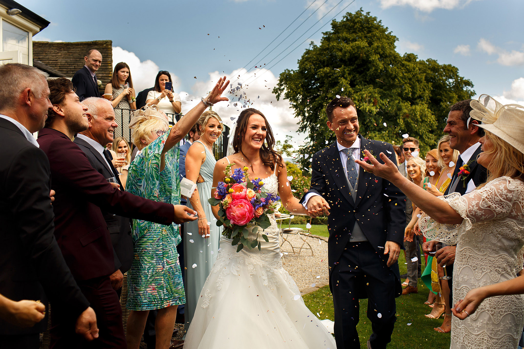 Bride and groom walking through confetti throwing in the garden at Shireburn Arms