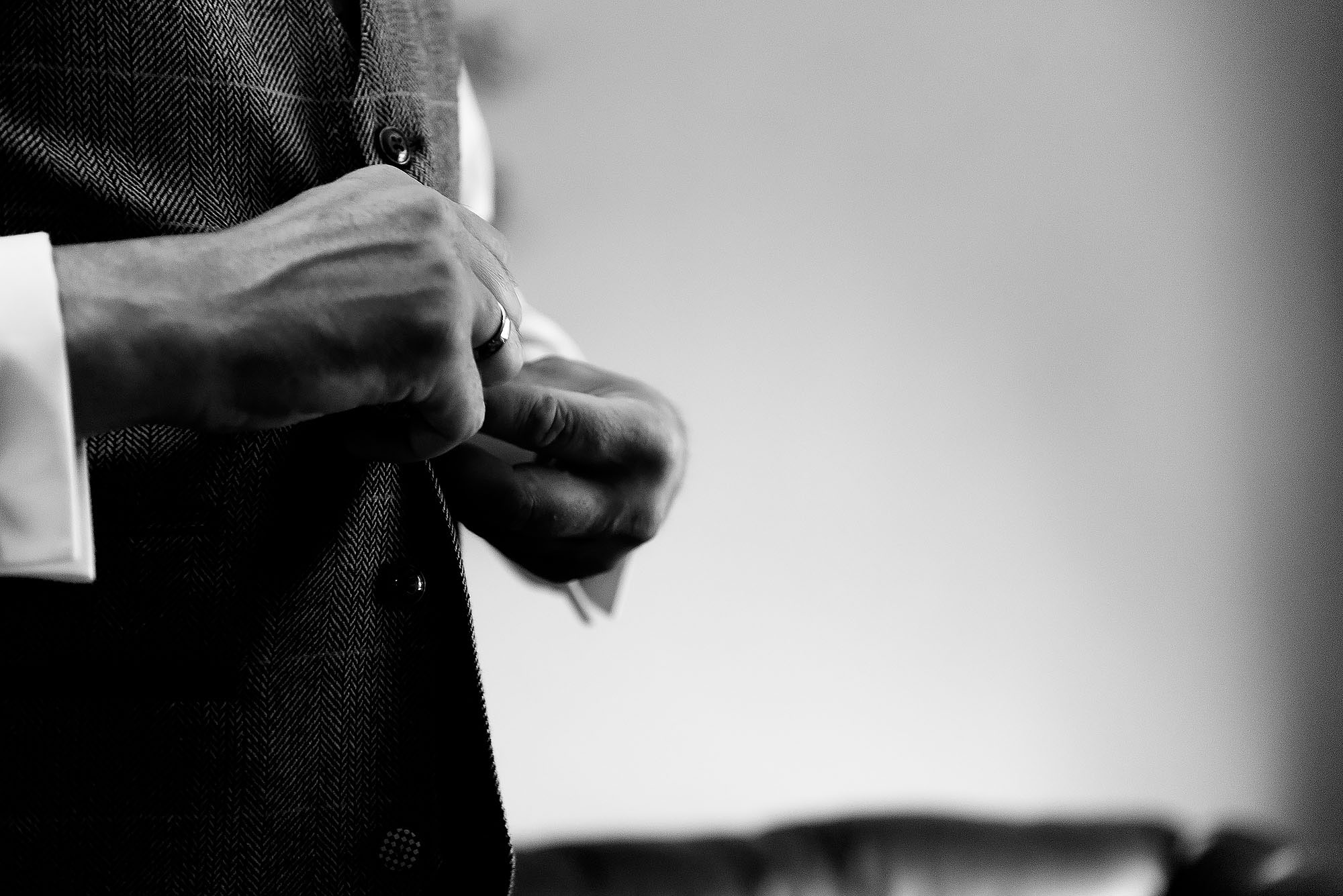 Close up of groom fastening tweed waistcoat on wedding morning | Wellbeing Farm wedding photographs by Toni Darcy Photography