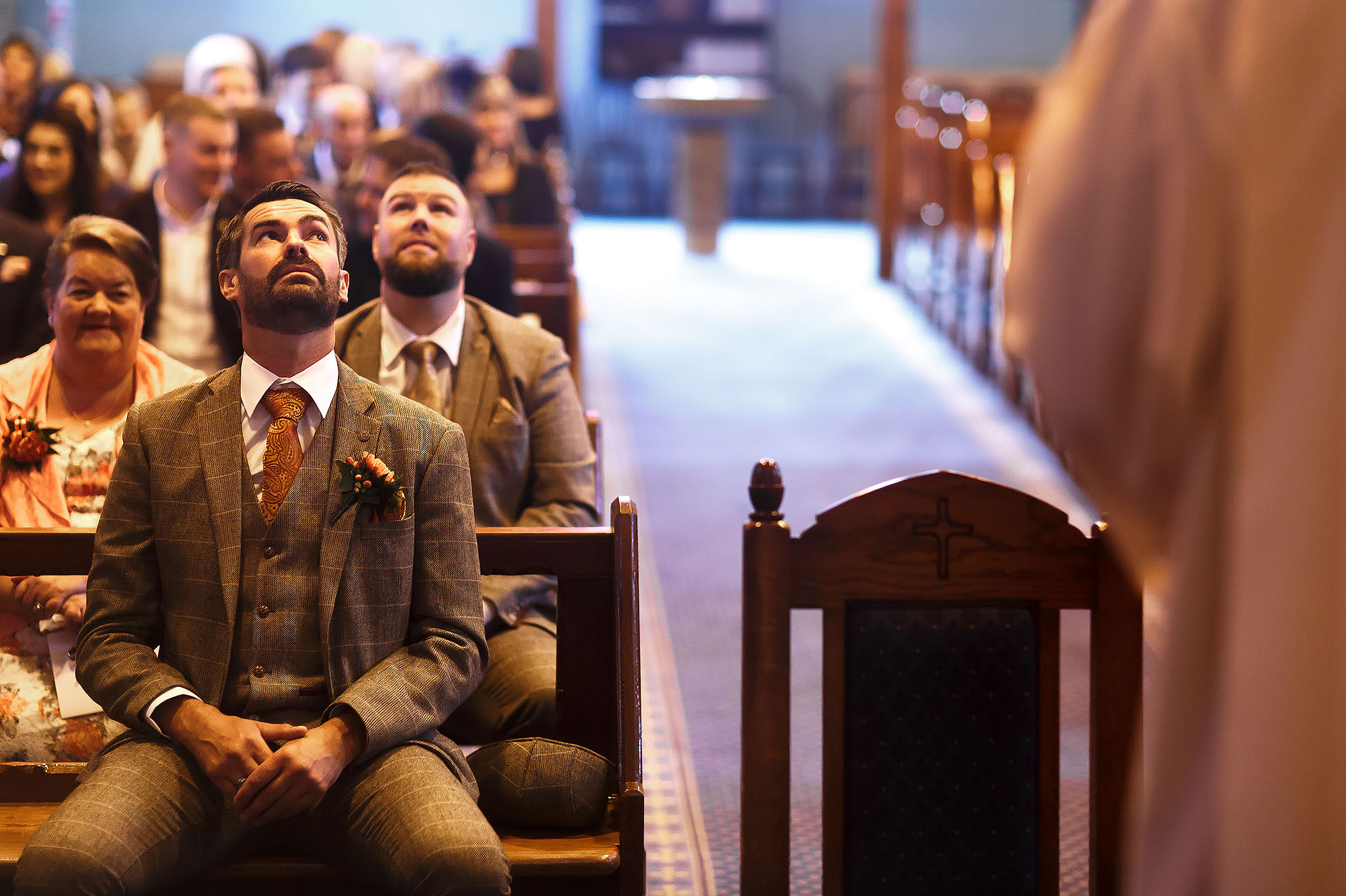 Groom looking nervously upwards as the church is full waiting for the bride to walk down the aisle at St James the Less Rawtenstall | Wellbeing Farm wedding photographs by Toni Darcy Photography