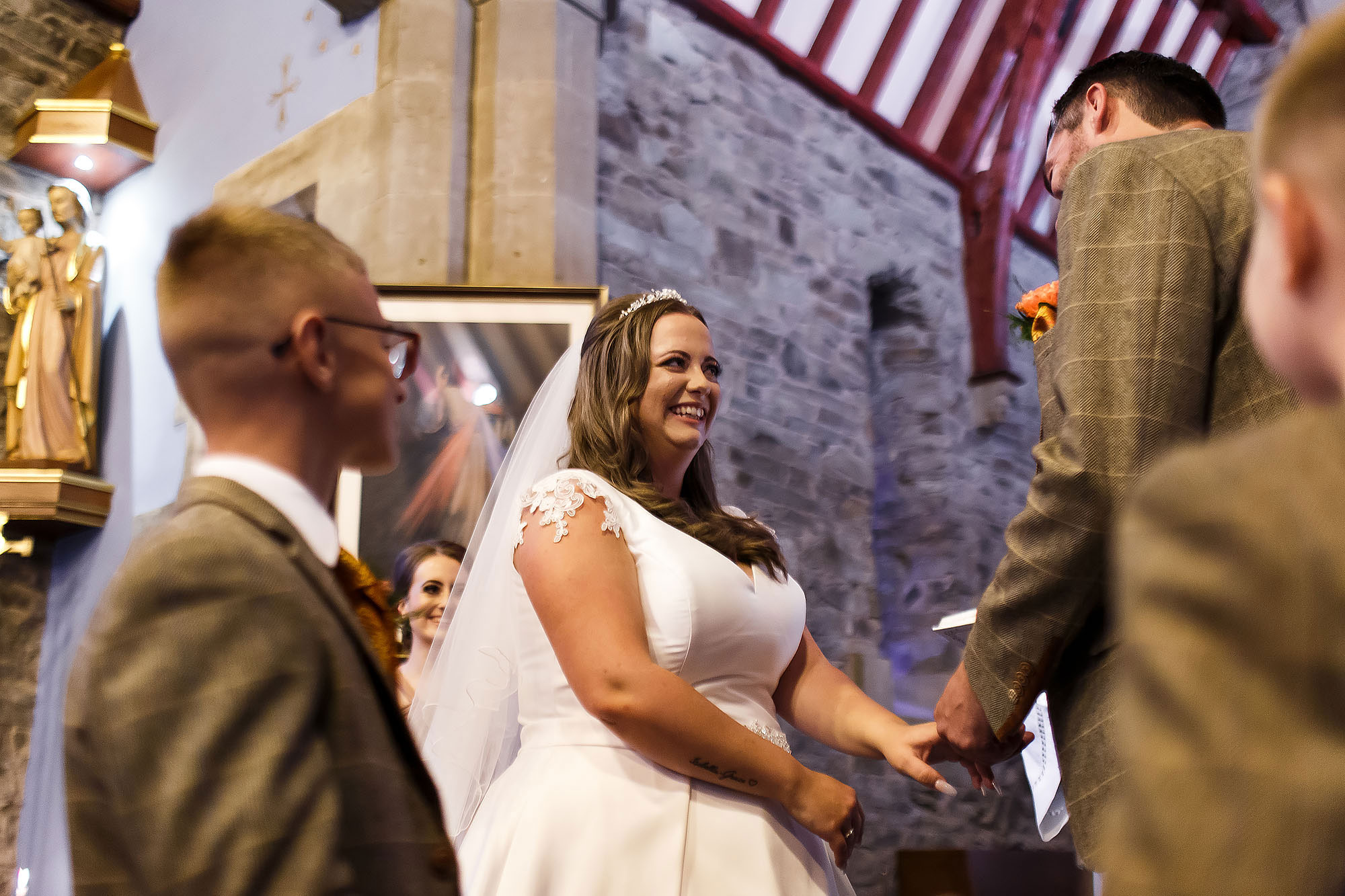 Bride laughing at the altar as page boys pass the wedding rings | Wellbeing Farm wedding photographs by Toni Darcy Photography