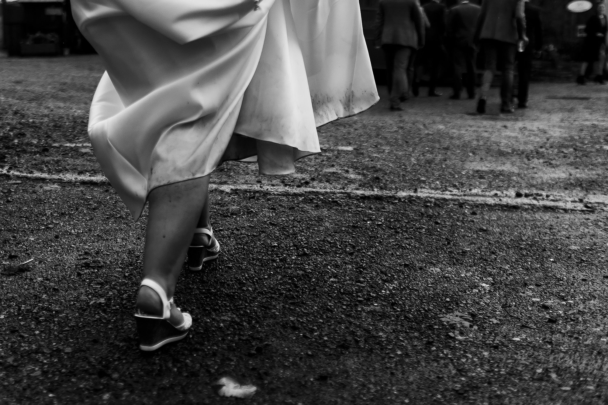 Bride holding dress high showing dirt and rain down the leg as she walks to wedding reception at Wellbeing Farm | Wellbeing Farm wedding photographs by Toni Darcy Photography