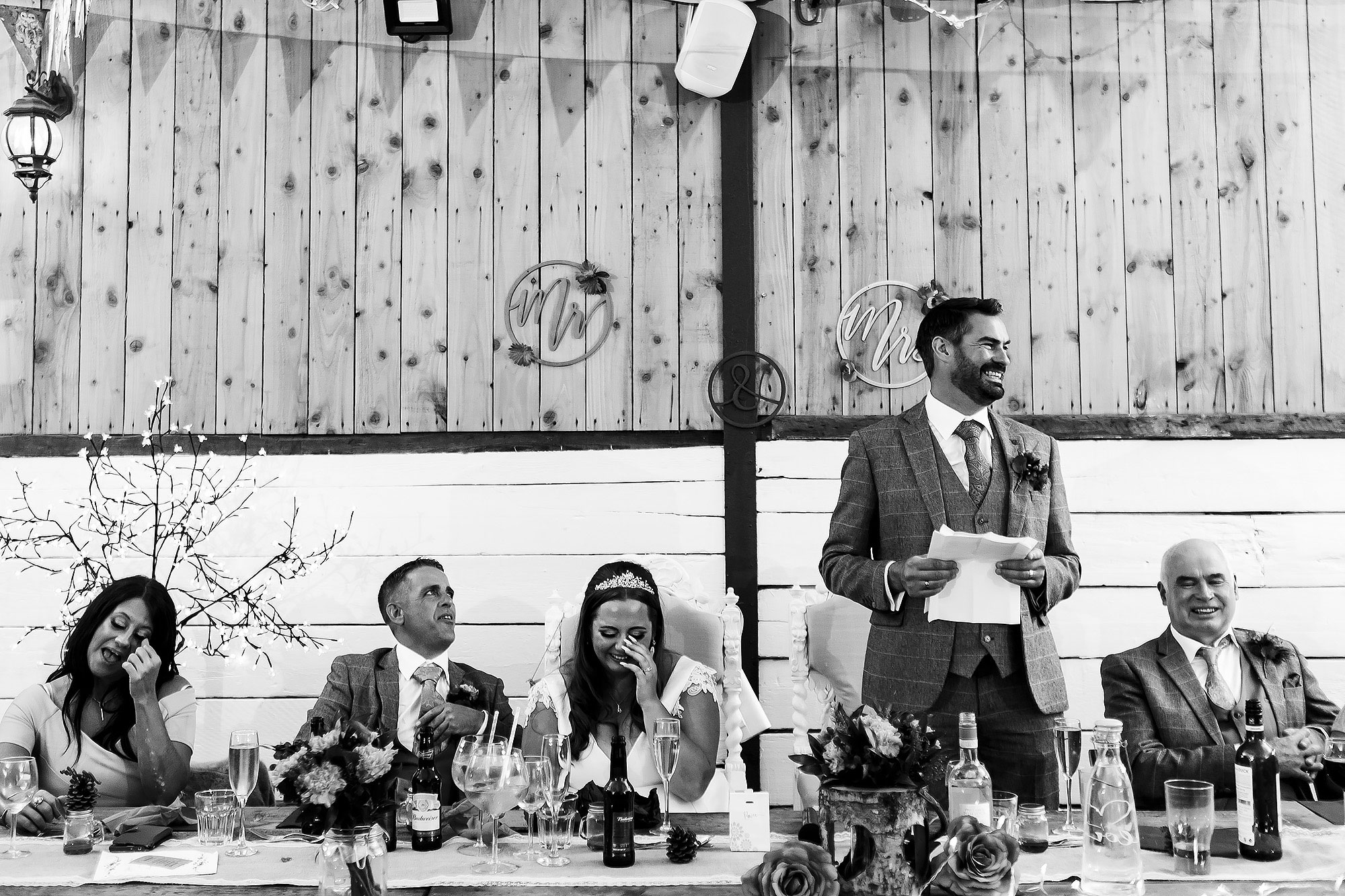 Top table of wedding guests crying laughing during speeches | Wellbeing Farm wedding photographs by Toni Darcy Photography