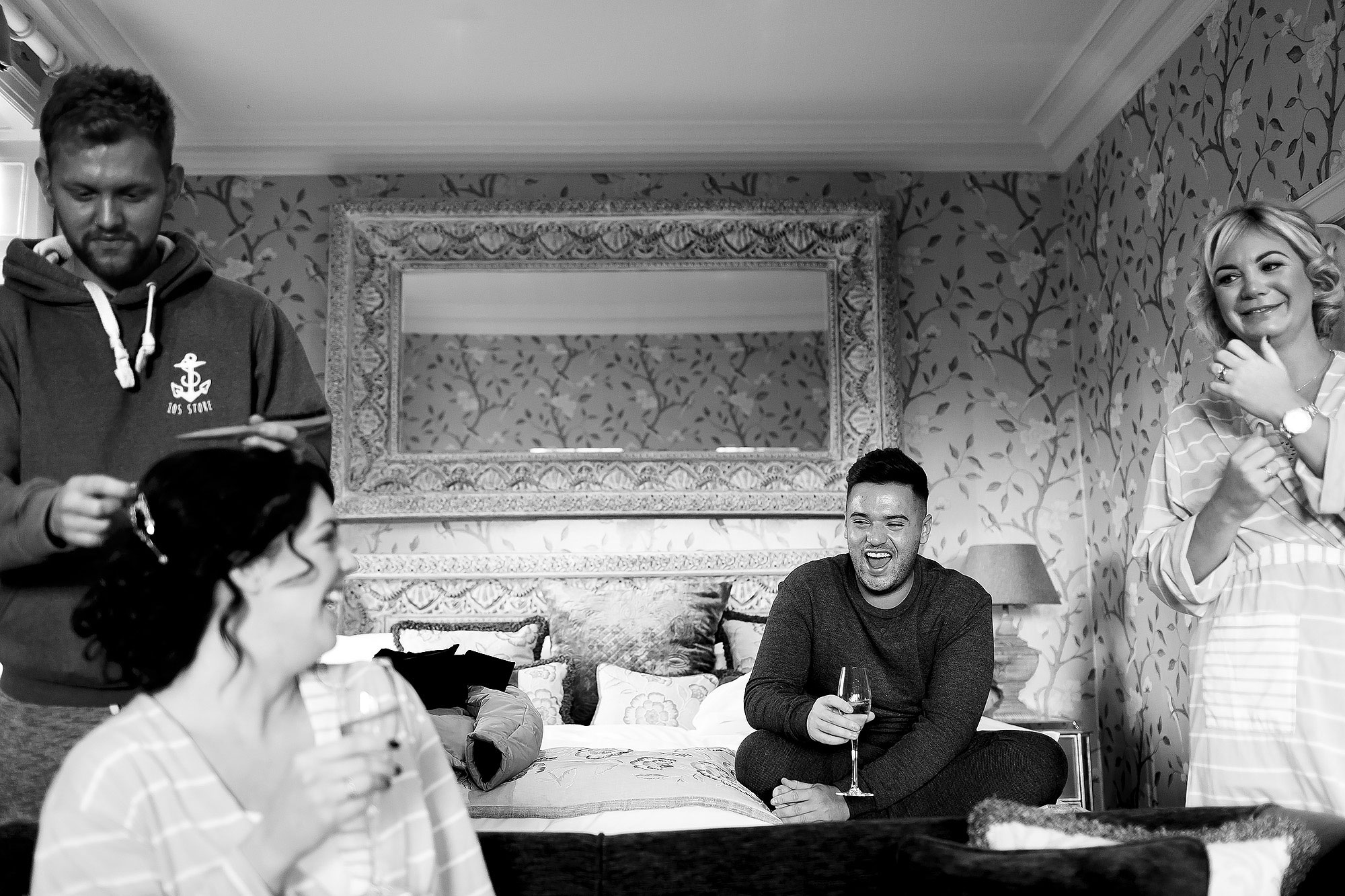 Bride and bridesmaids laughing drinking champagne in the bridal suite | Eaves Hall wedding photography by Toni Darcy