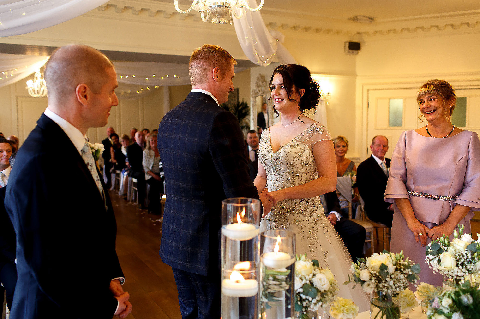 Bride and groom facing one another during wedding ceremony as the witnesses stand forward | Eaves Hall wedding photography by Toni Darcy