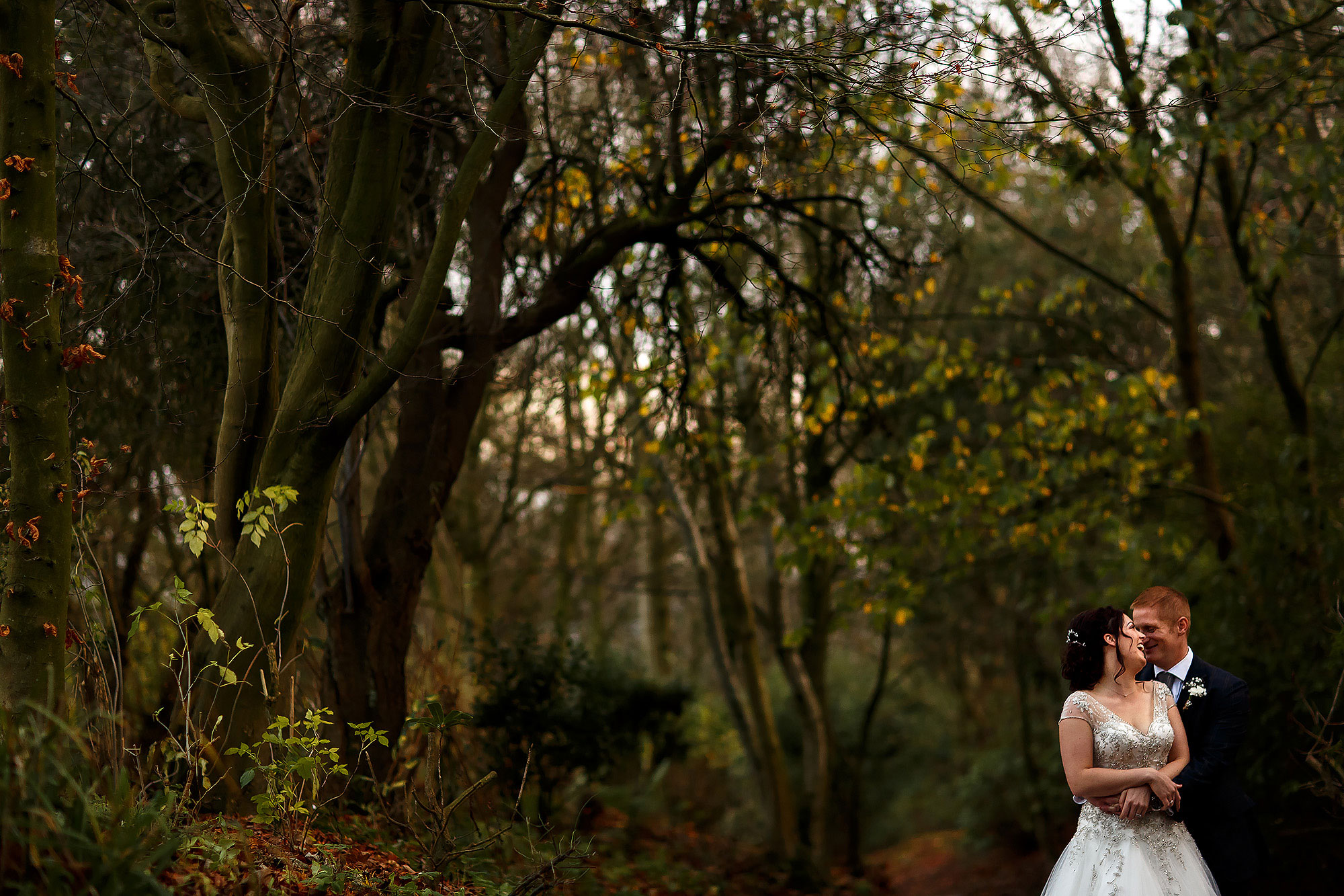 Bride and groom wrapped in each others arms in the tree lined walkway | Eaves Hall wedding photography by Toni Darcy