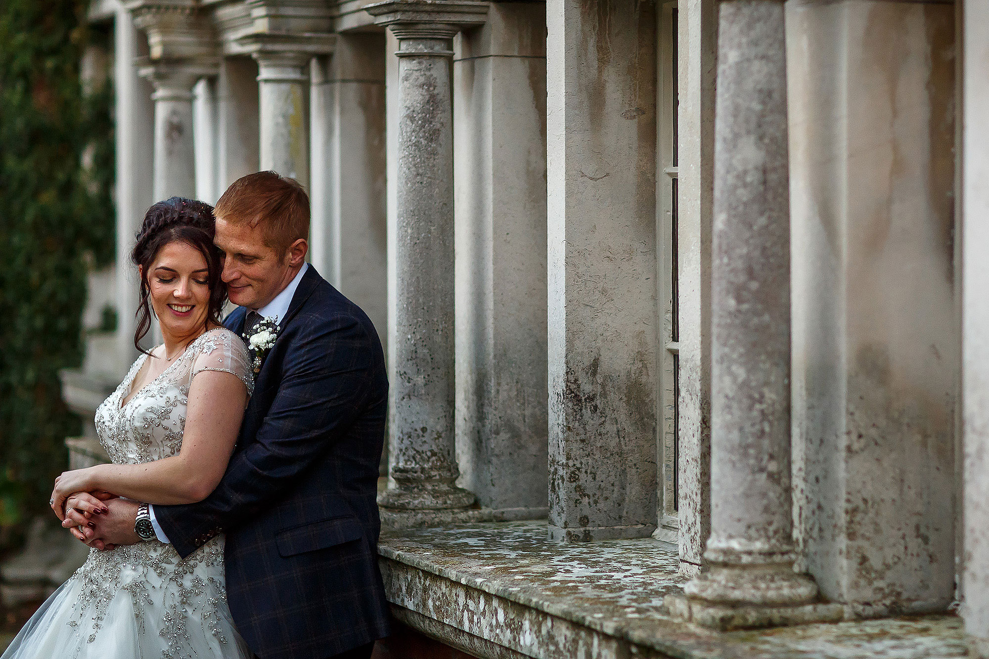 Bride and groom holding each other tight in front of the pillared windows | Eaves Hall wedding photography by Toni Darcy