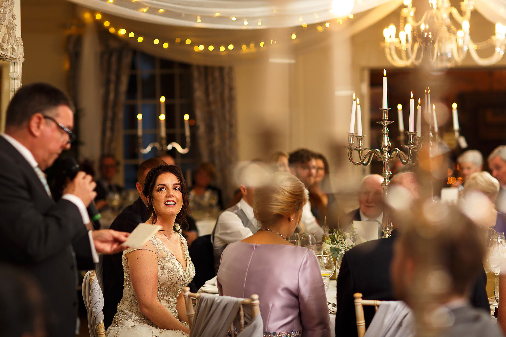 Bride looking towards her father as he makes a speech to all the wedding guests | Eaves Hall wedding photography by Toni Darcy