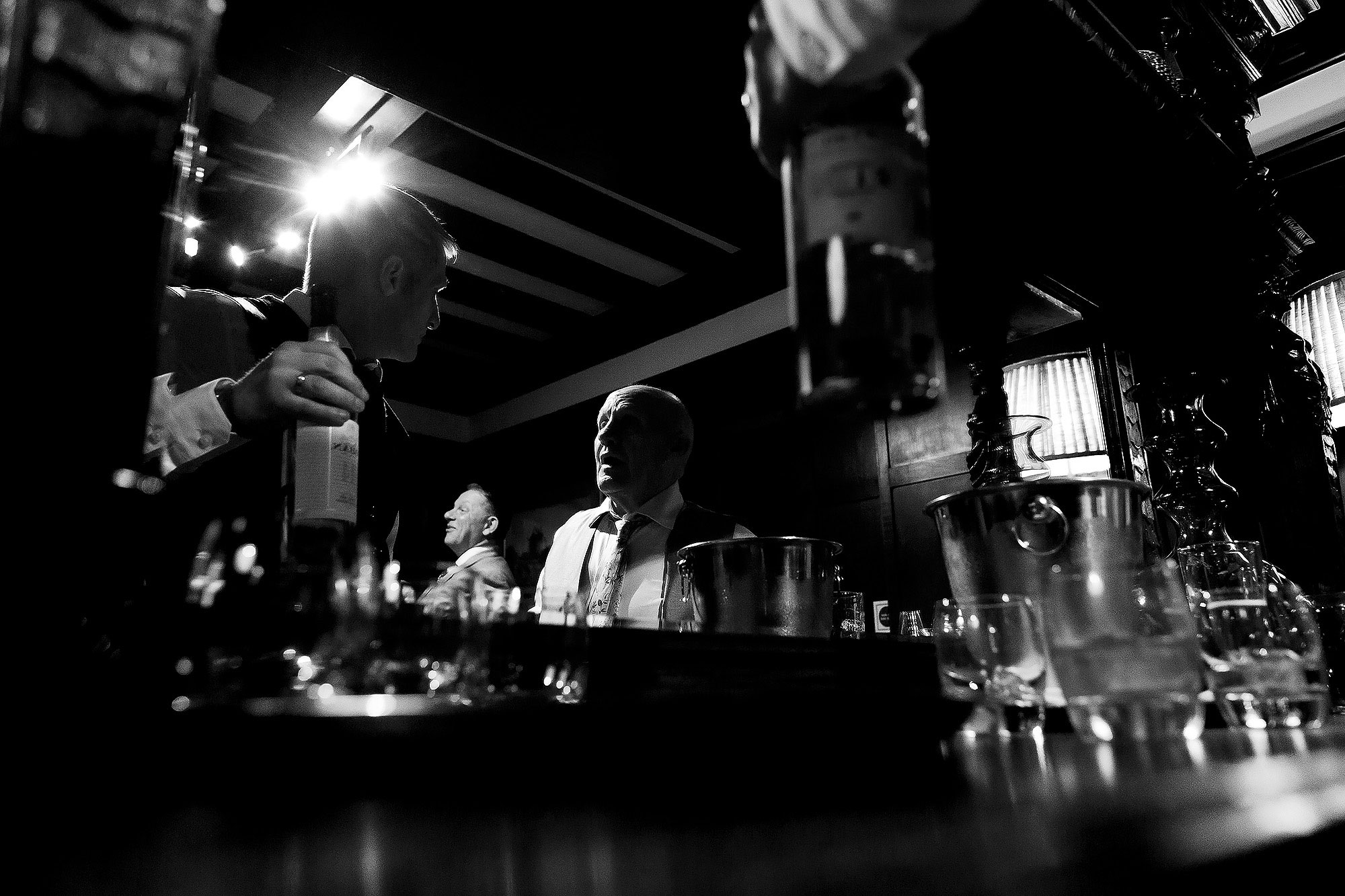 Groom having whiskey in the pool room with wedding guests | Eaves Hall wedding photography by Toni Darcy